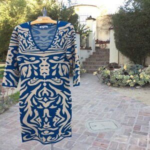 May include: A blue and beige patterned sweater dress with a v-neck and three-quarter sleeves.
