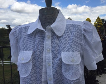 Blusa Baby Doll blanca transparente, talla 10 (mediana), con pequeñas margaritas que recuerdan a las de Mary Quant, mangas abullonadas de algodón y poliéster, botones en la parte delantera.