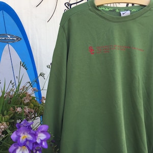 May include: Green long-sleeved sweatshirt with a red embroidered logo that reads "University of Southern California Trojans Est. 1880".