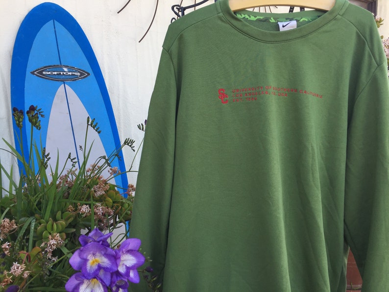 May include: Green long-sleeved sweatshirt with a red embroidered logo that reads "University of Southern California Trojans Est. 1880".
