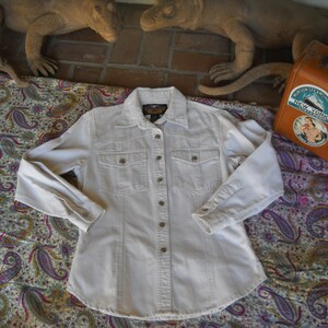 May include: A white long-sleeved button-down shirt with a single chest pocket and a button-down collar.