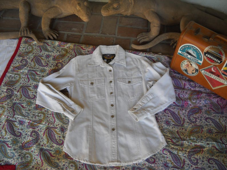 May include: A white long-sleeved button-down shirt with a single chest pocket and a button-down collar.