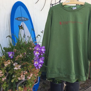 May include: Green long-sleeved sweatshirt with a red embroidered logo that reads "University of Southern California Trojans 1974".