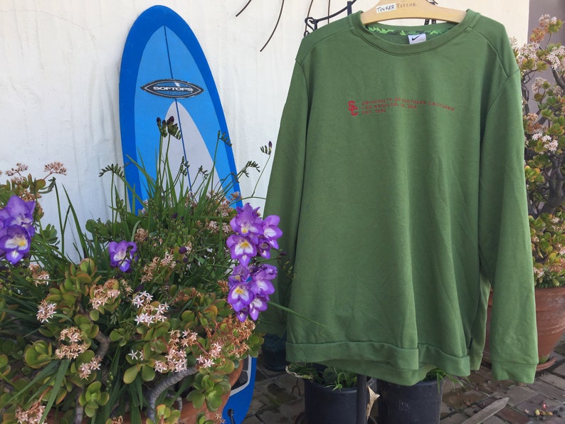 May include: Green long-sleeved sweatshirt with a red embroidered logo that reads "University of Southern California Trojans 1974".