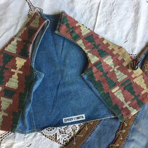 K&ouml;nnte beinhalten: Eine Jeansweste mit einem bunten, gemusterten Stoffbesatz. Die Weste hat ein Etikett mit der Aufschrift "Jensen Smith".