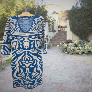 May include: A blue and beige patterned sweater dress with a v-neck. The dress is on a hanger and has a tag that says "Lauren Ralph Lauren".