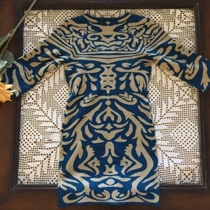 May include: A blue and beige patterned sweater dress with a long sleeve and a crew neck.