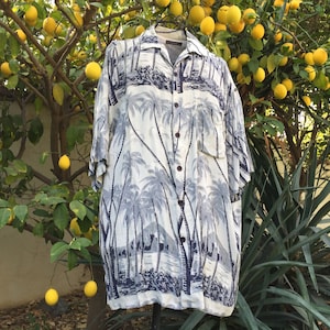 May include: A white and blue short-sleeved button-down shirt with a palm tree print. The shirt has a pocket on the left side.