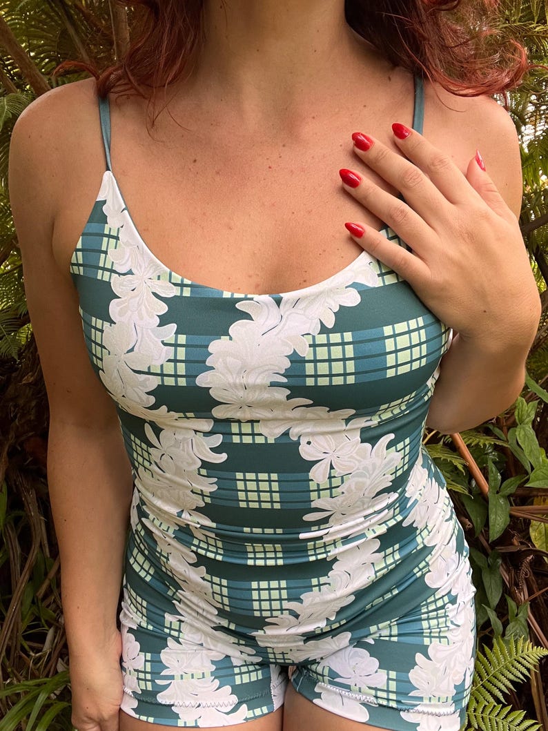 Op de afbeelding: Een blauwgroene en lichtgroene geruite romper met een wit bloemenrankpatroon. Het kledingstuk heeft een ronde halslijn en dunne spaghettibandjes, met een nauwsluitend silhouet dat loopt van het lijfje tot aan de korte zoom.
