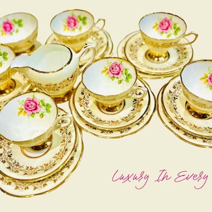 May include: A set of vintage teacups and saucers with a floral rose design. The white porcelain cups and saucers have gold trim and a pink rose in the center. A creamer is also included. The text "Luxury In Every Sip" is written in cursive.