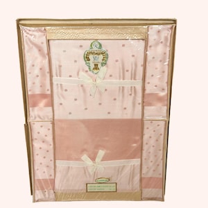 Op de afbeelding: Een set van een rayon tafelkleed en servetten in een doos. De set bevat een roze tafelkleed met kleine stippen en bijpassende servetten. De set is vastgebonden met witte strikken. De doos heeft een lichtbruine kleur.