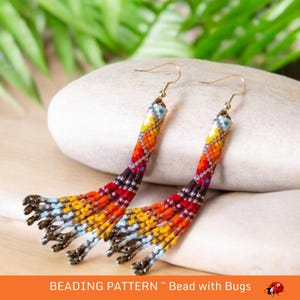 May include: A pair of long, beaded earrings with a colorful geometric pattern in shades of red, orange, yellow, blue, and white. The earrings are made with small seed beads and have a tassel-like fringe at the bottom.