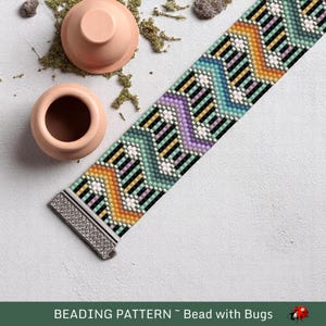 May include: A beaded bracelet with a colorful chevron pattern in shades of orange, green, purple, and black. The bracelet has a silver clasp.