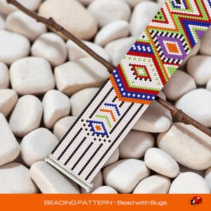 May include: A beaded bracelet pattern with a colorful geometric design. The pattern features white, black, red, blue, orange, green, and purple beads. The bracelet is displayed on a bed of white stones with a small branch.
