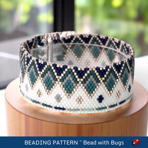 Könnte beinhalten: Ein Armband aus Perlen mit einem geometrischen Muster in Blautönen, Grün, Weiß und Gold. Das Armband ist aus kleinen Perlen gefertigt und hat einen Verschluss.