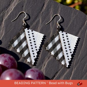 May include: A pair of black and white geometric beaded earrings with silver hooks. The earrings are shaped like a diamond and have a black and white striped pattern.
