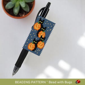 May include: A black pen with a beaded Halloween-themed pen wrap. The wrap features a dark blue background with orange pumpkins and black cats. The text "BEADING PATTERN ~ Bead with Bugs" is at the bottom.