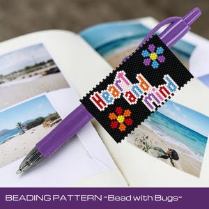 Puede incluir: Un bolígrafo morado con un diseño de cuentas negro que dice "Heart and Mind" en cuentas coloridas, con diseños de flores. El bolígrafo descansa sobre un cuaderno con fotos de playa.