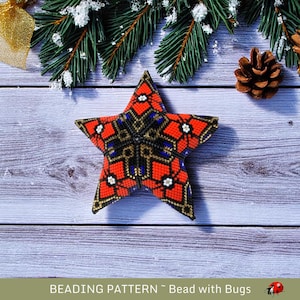 May include: A red, black, and gold beaded star ornament with a snowflake design. The star is sitting on a wooden surface with a pine branch and pine cone in the background.