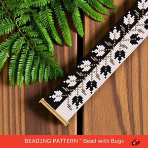 May include: A beaded bracelet pattern with a floral design in black, white, and beige. The bracelet is shown on a wooden surface with green fern leaves. The text "BEADING PATTERN ~ Bead with Bugs" is at the bottom.