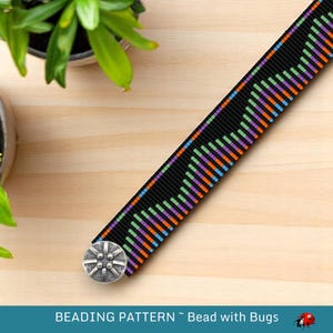 Puede incluir: Una pulsera de cuentas negras con un patrón geométrico en azul, verde, naranja y morado. La pulsera tiene un cierre de botón plateado. El texto "BEADING PATTERN ~ Bead with Bugs" está en la parte inferior de la imagen.