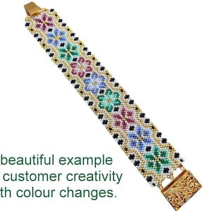 May include: A white beaded bracelet with a gold clasp. The bracelet features a repeating pattern of colorful flowers and black beads.