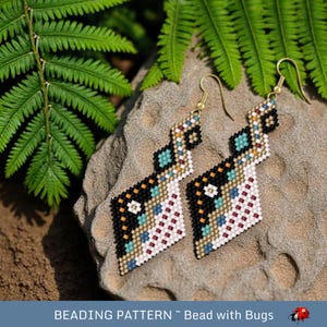 Op de afbeelding: Een paar kralen oorbellen met een geometrisch ontwerp. De oorbellen hebben een patroon van zwarte, witte, teal en gouden kralen. De oorbellen worden getoond op een steen met groene varens op de achtergrond. De tekst "BEADING PATTERN ~ Bead with Bugs" staat onderaan.