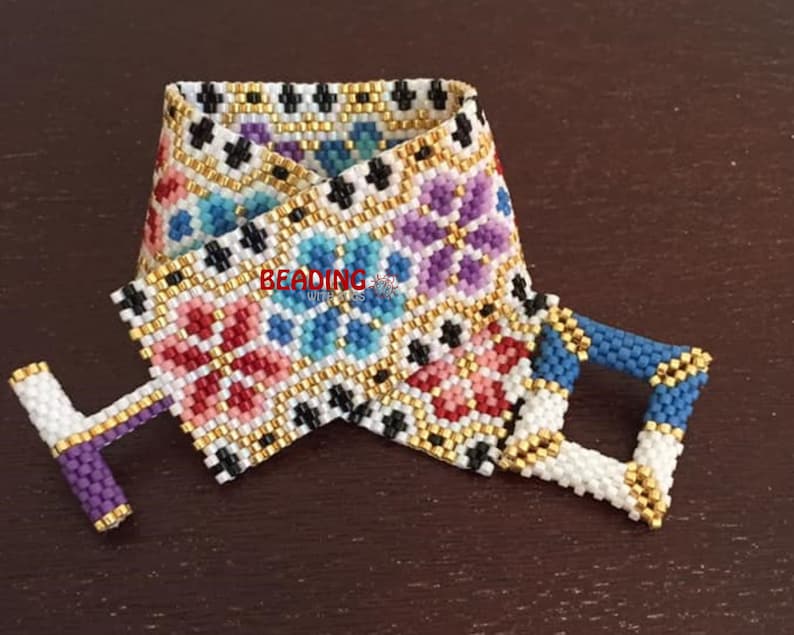 May include: A white beaded bracelet with a colorful floral pattern and gold accents. The bracelet has a clasp closure.