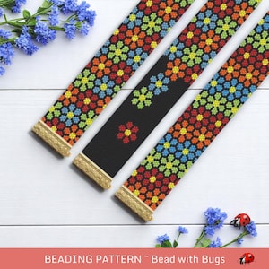 Könnte beinhalten: Drei Perlenarmbänder mit einem bunten Blumenmuster. Die Armbänder liegen auf einer weißen Holzoberfläche mit blauen Blumen und einem Marienkäfer.