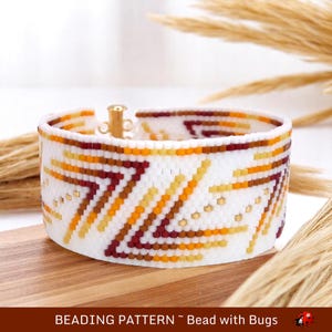 May include: A white beaded bracelet with a geometric pattern in shades of brown, orange, and yellow. The bracelet has a gold clasp.