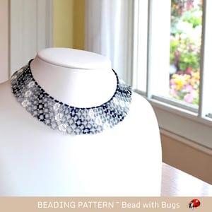 May include: A beaded necklace with a geometric pattern in shades of grey and black. The necklace is displayed on a white mannequin bust.
