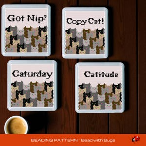 Könnte beinhalten: Vier quadratische, weiß gerahmte dekorative Kacheln mit Katzen-Kreuzstichmustern. Jede Kachel hat einen anderen Satz: "Got Nip?", "Copy Cat!", "Caturday" und "Catitude". Die Kacheln sind vor einem dunklen Holzgrund angeordnet.