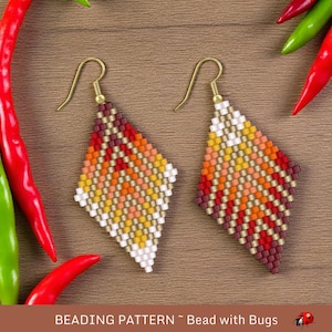 Può includere: Un paio di orecchini a forma di diamante realizzati con perline. Gli orecchini sono fatti con perline rosse, arancioni, gialle, bianche e dorate. Gli orecchini sono appesi a ganci dorati.
