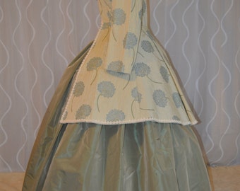 May include: A green and cream-colored dress with a floral pattern. The dress has a fitted bodice and a full skirt. The skirt is made of a smooth fabric and has a slight sheen.