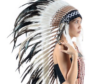 May include: A woman wearing a black and white feathered headdress with a black and white beaded necklace. She is wearing black pants and a black top.