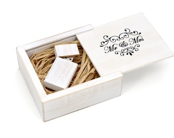 May include: White wooden box with a hinged lid. The lid has a black inscription that reads "Mr. & Mrs." The box contains two small white wooden USB drives.