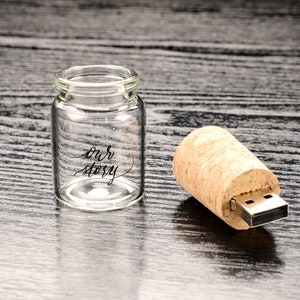 May include: A small glass bottle with a cork top USB drive. The bottle has the words "our story" written on it.