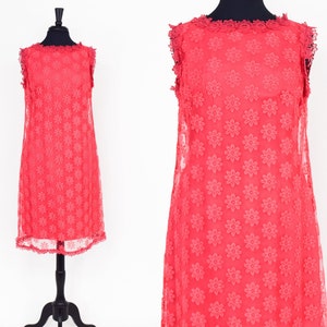 May include: A sleeveless coral pink dress with a floral pattern and a scalloped neckline.