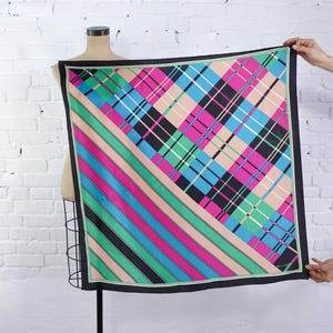 Peut inclure: Un foulard carré en soie présentant un motif géométrique audacieux divisé en diagonale. Une moitié affiche un motif écossais vibrant en rose vif, turquoise, vert, noir et beige, tandis que l'autre moitié présente des rayures diagonales parallèles.