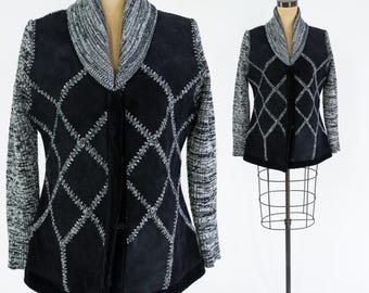 May include: Black and white knit cardigan with a suede panel and diamond pattern. The cardigan has a shawl collar and a button closure.