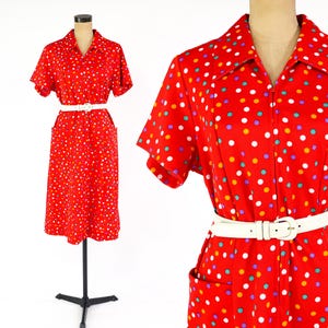 May include: A vintage red dress with a white belt and colorful polka dots. The dress has short sleeves, a collared neckline, and a zipper closure. The dress is displayed on a mannequin.