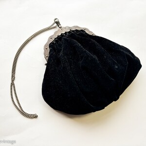 May include: A black velvet evening bag with a silver chain strap and a decorative metal clasp.