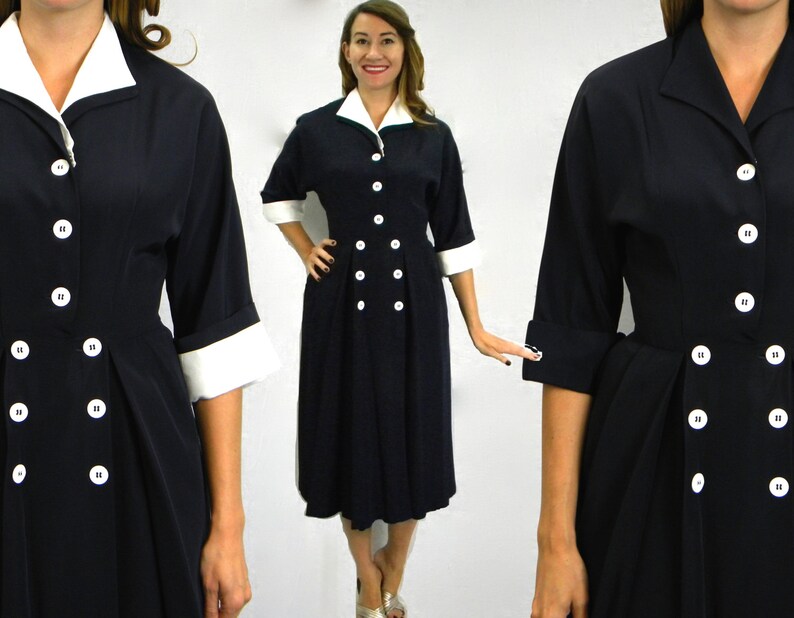 Pode incluir: Um vestido azul marinho com colarinho e punhos brancos. O vestido tem fecho de bot&otilde;es de dupla abotoadura e saia plissada.