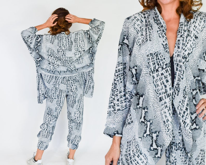 May include: A white and black patterned pantsuit with a long, open-front jacket. The fabric has a snake skin print.