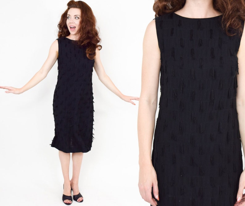 May include: A black sleeveless dress with a textured fringe design. The dress is knee-length and has a scoop neckline.