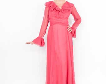 May include: A long, pink, ruffled dress with long sleeves and a V-neckline. The dress is made of a sheer fabric and has a flowing silhouette.