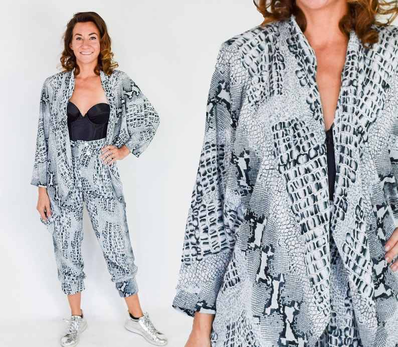 May include: A black and white snake print two-piece outfit. The top is a long-sleeved, open-front jacket. The pants are loose-fitting and cropped.