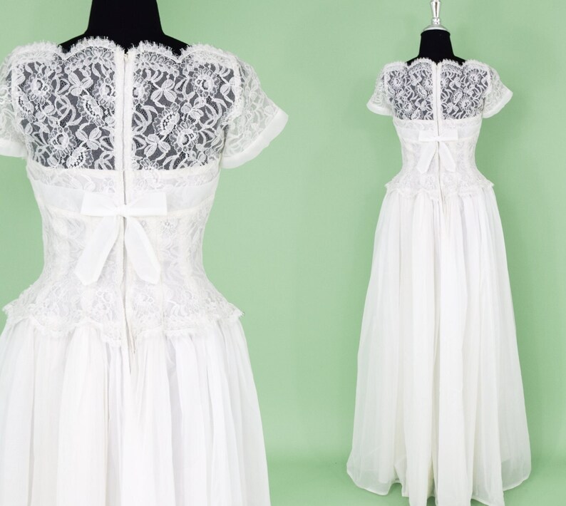 Puede incluir: Un vestido de novia blanco de encaje con un corpi&ntilde;o ajustado y una falda completa. El vestido tiene una superposici&oacute;n de encaje y un lazo en la espalda.