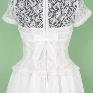 Puede incluir: Vestido de novia blanco de encaje con un lazo en la espalda y una cremallera.