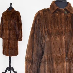 May include: A long brown fur coat with a collar and button closure.